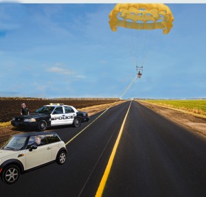 A police officer waits for parasailer Loonis Twohey to drift to the ground while Emmet Kefauver waits in his car